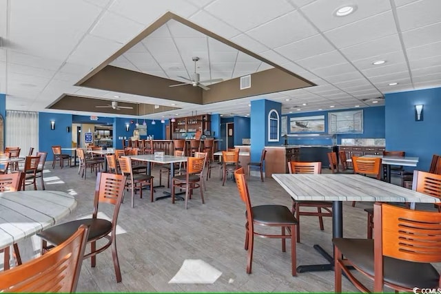 dining room with wood finished floors, a ceiling fan, visible vents, and a drop ceiling