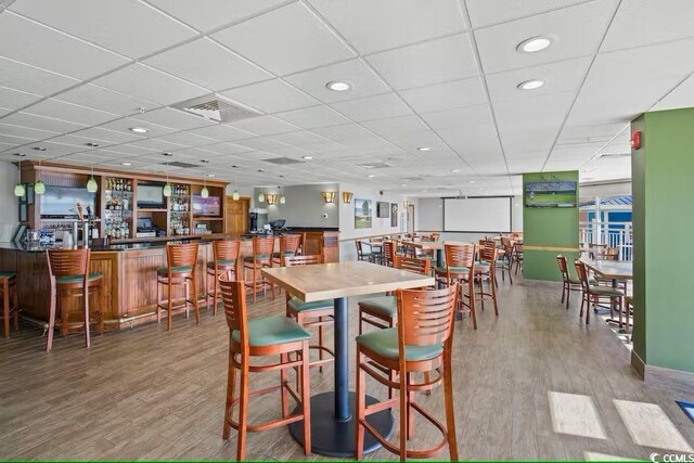 dining area featuring visible vents, a community bar, wood finished floors, and recessed lighting