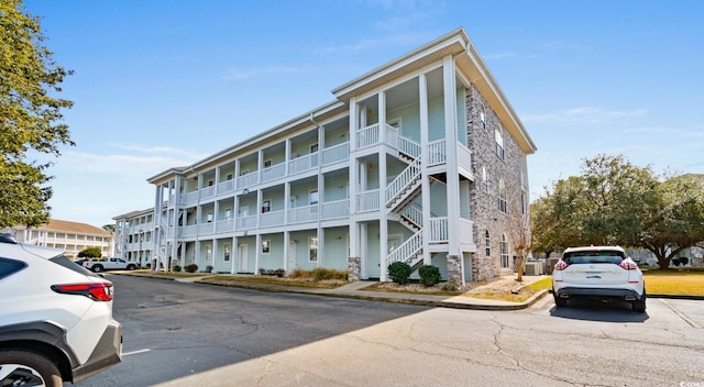 view of building exterior with stairs and uncovered parking