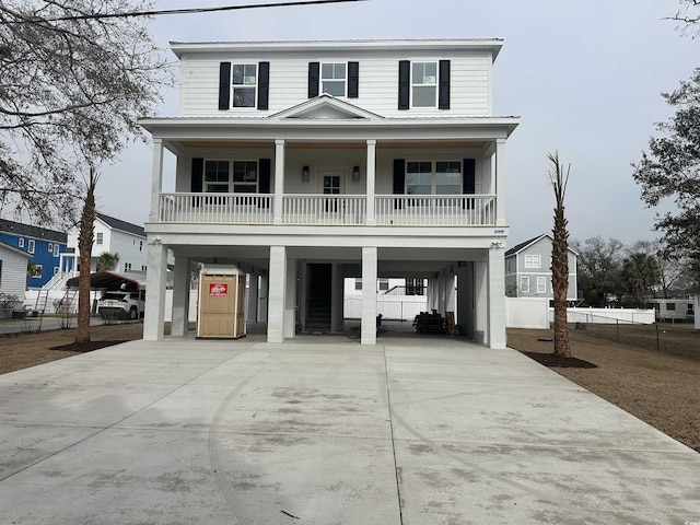 coastal inspired home featuring a carport, covered porch, driveway, and fence