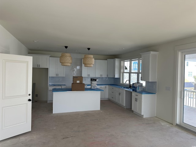 kitchen featuring tasteful backsplash, a kitchen island, a sink, and a healthy amount of sunlight