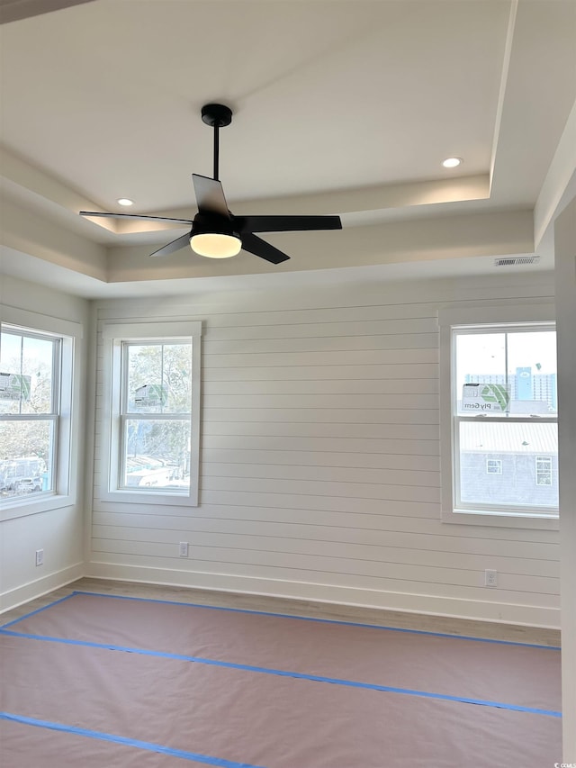 spare room featuring a tray ceiling, a healthy amount of sunlight, and recessed lighting