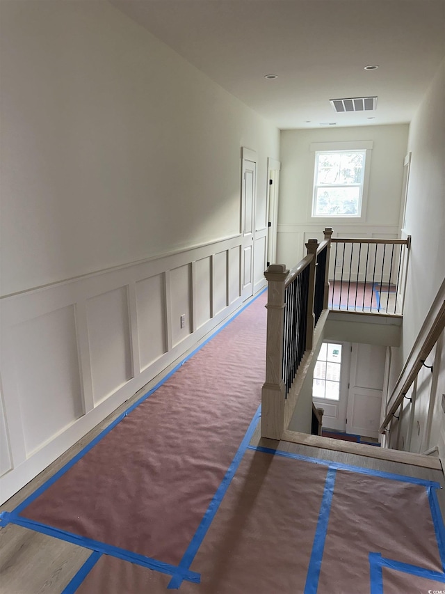 stairway featuring visible vents, a decorative wall, and carpet flooring