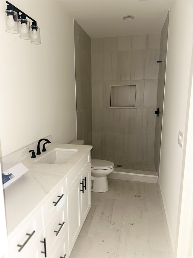 full bath with toilet, a stall shower, baseboards, and vanity