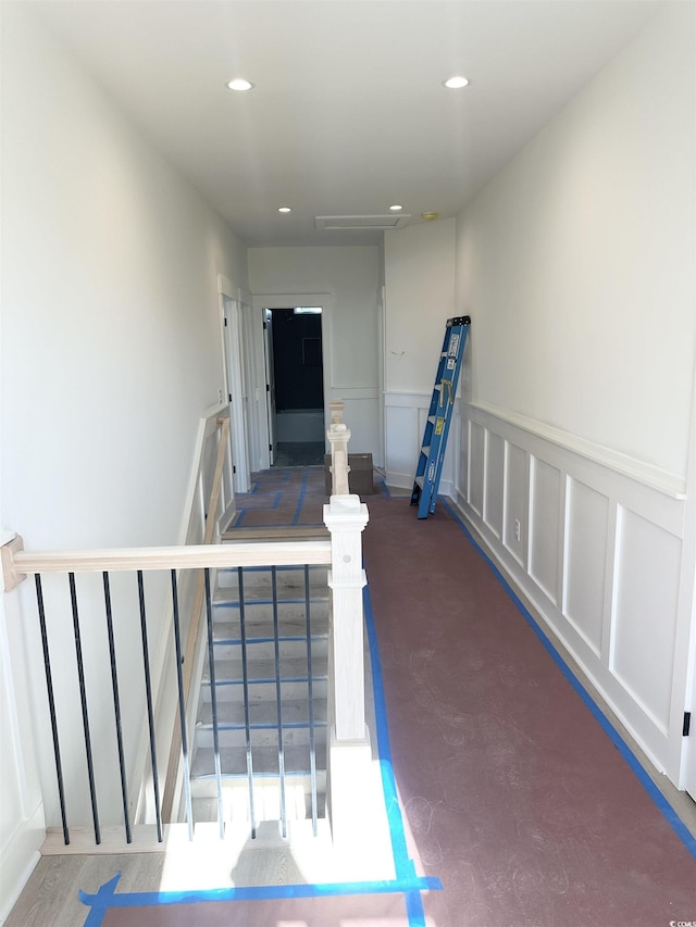 stairway featuring a wainscoted wall, recessed lighting, and a decorative wall