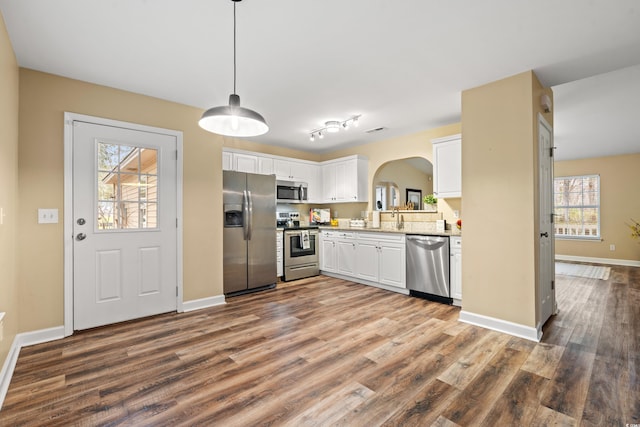 kitchen featuring stainless steel appliances, white cabinetry, hanging light fixtures, and wood finished floors