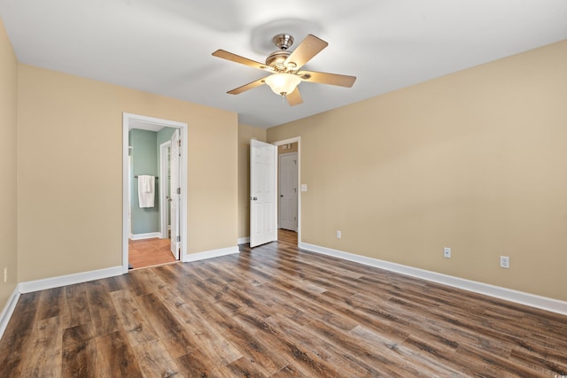 unfurnished bedroom with baseboards, dark wood finished floors, a ceiling fan, and ensuite bathroom