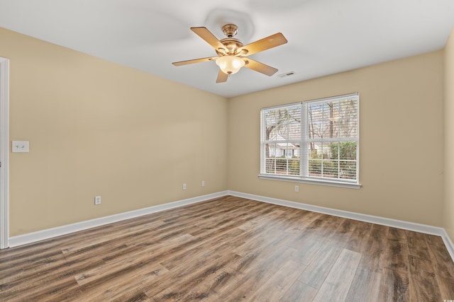 empty room with a ceiling fan, visible vents, baseboards, and wood finished floors