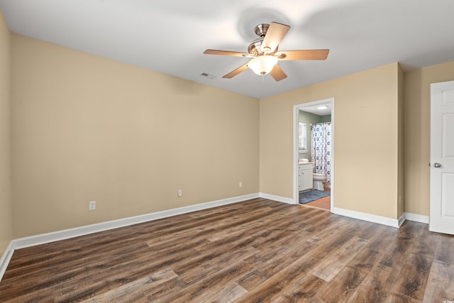 unfurnished bedroom with dark wood finished floors, visible vents, a ceiling fan, connected bathroom, and baseboards