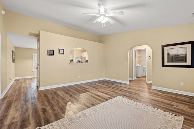 empty room with arched walkways, ceiling fan, baseboards, and wood finished floors