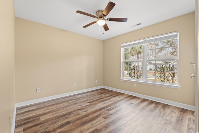 empty room with visible vents, ceiling fan, baseboards, and wood finished floors