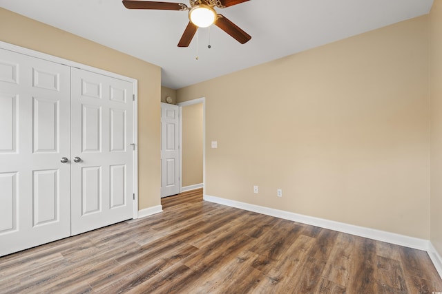 unfurnished bedroom featuring ceiling fan, a closet, wood finished floors, and baseboards