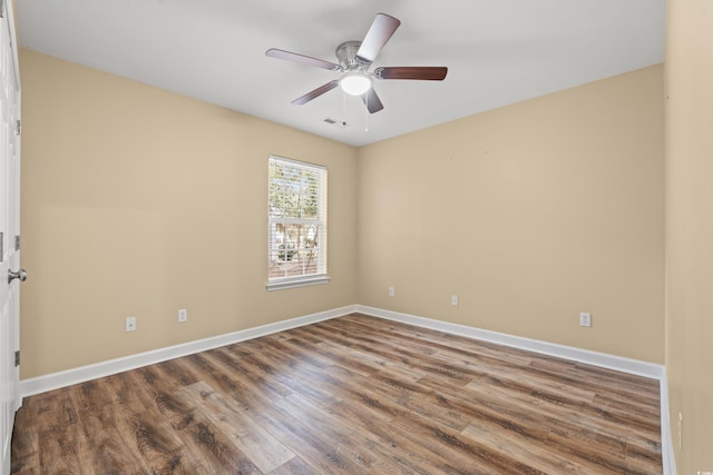 empty room with ceiling fan, wood finished floors, visible vents, and baseboards