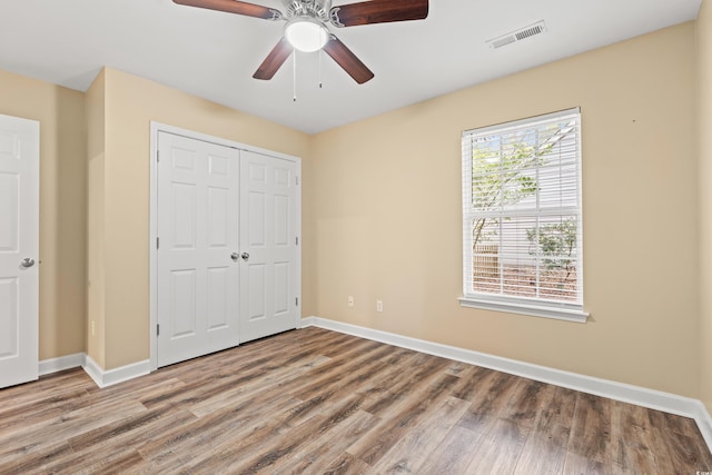 unfurnished bedroom featuring a closet, visible vents, baseboards, and wood finished floors