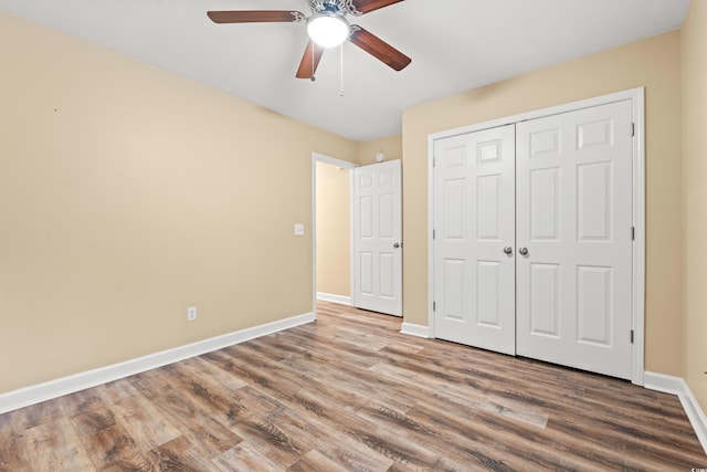 unfurnished bedroom with ceiling fan, a closet, wood finished floors, and baseboards