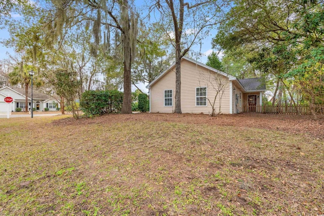 view of home's exterior featuring fence and a lawn