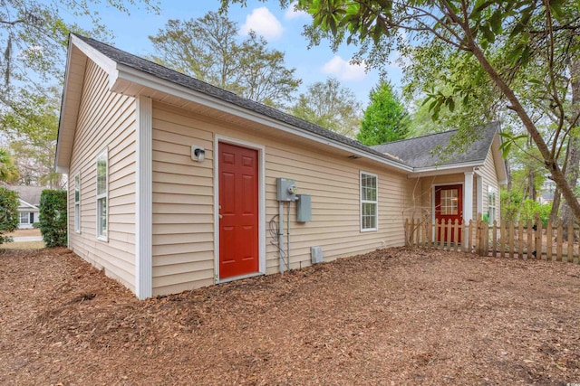 exterior space with a shingled roof and fence