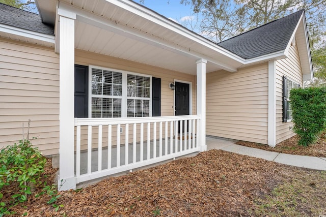 view of exterior entry featuring a porch and roof with shingles