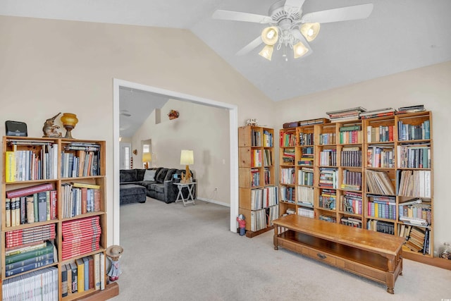 living area with carpet floors, bookshelves, vaulted ceiling, and a ceiling fan