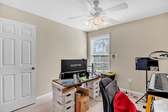 office area featuring a textured ceiling, baseboards, a ceiling fan, and light colored carpet