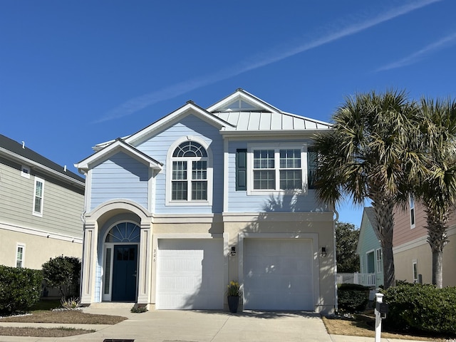 view of front facade with metal roof, an attached garage, driveway, stucco siding, and a standing seam roof