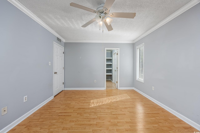 unfurnished room with crown molding, a textured ceiling, visible vents, and light wood-style floors