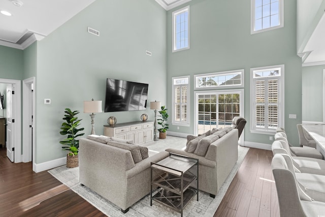 living room featuring baseboards, visible vents, wood finished floors, and ornamental molding