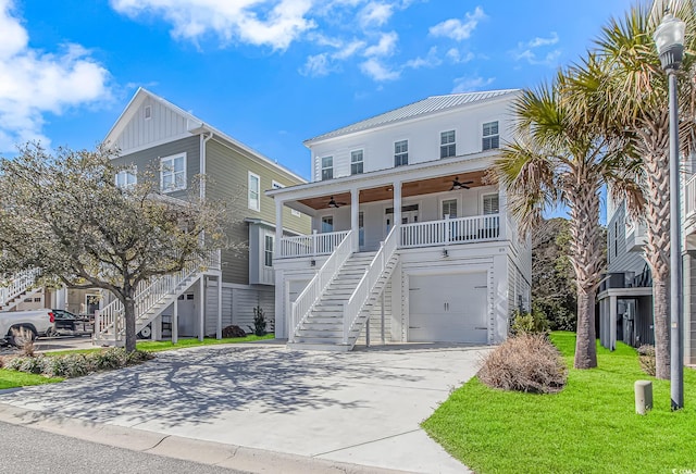 raised beach house featuring covered porch, stairway, ceiling fan, driveway, and a front lawn