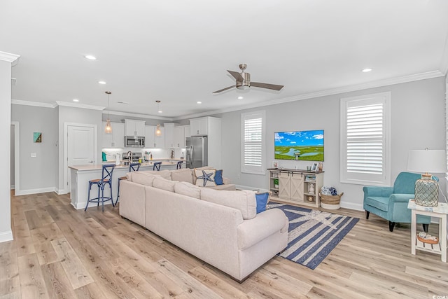 living area with ornamental molding, recessed lighting, baseboards, and light wood finished floors