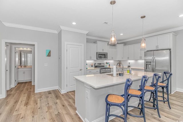 kitchen featuring light countertops, visible vents, appliances with stainless steel finishes, ornamental molding, and a sink