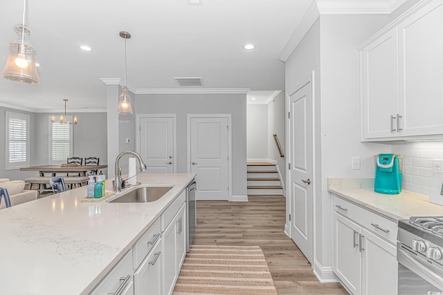 kitchen featuring a sink, visible vents, white cabinets, ornamental molding, and light wood-type flooring