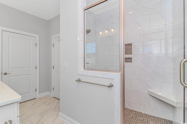 bathroom featuring marble finish floor, vanity, baseboards, and a stall shower