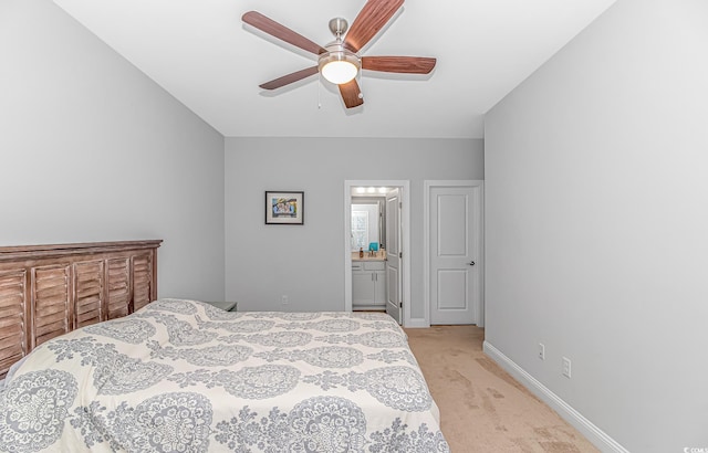 bedroom with a ceiling fan, light colored carpet, baseboards, and ensuite bathroom