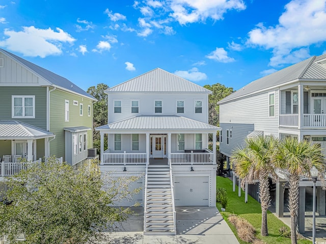 raised beach house with driveway, metal roof, stairs, a porch, and a front yard