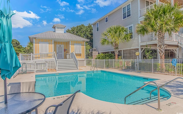 community pool with a patio area and fence