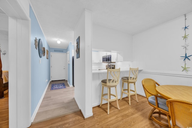 interior space with crown molding, light wood-style flooring, and baseboards