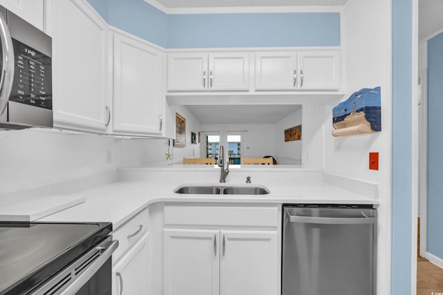 kitchen featuring stainless steel appliances, white cabinets, light countertops, and a sink