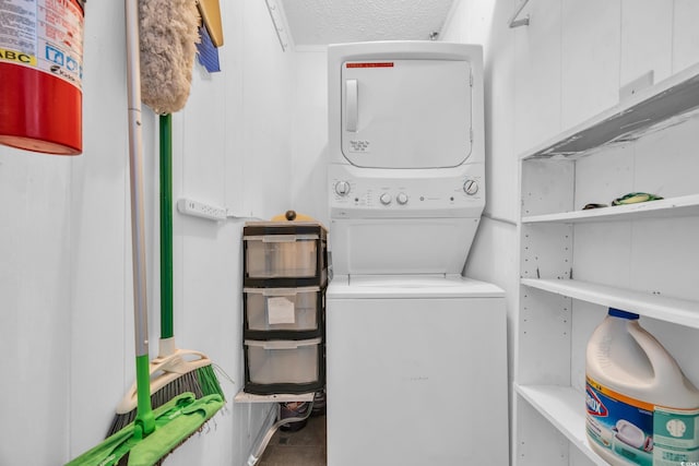 laundry area with stacked washer and dryer, laundry area, and a textured ceiling