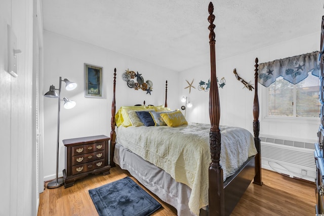 bedroom with a textured ceiling, radiator heating unit, and wood finished floors