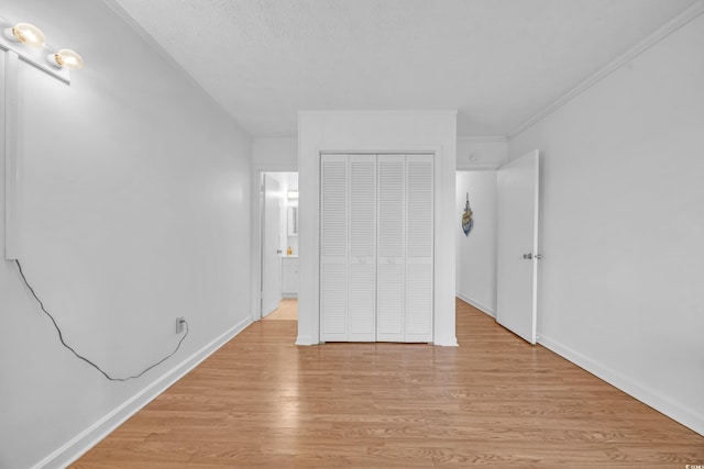 unfurnished bedroom with a textured ceiling, a closet, light wood-type flooring, and baseboards