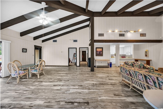 living area with ceiling fan, visible vents, wood finished floors, and beam ceiling