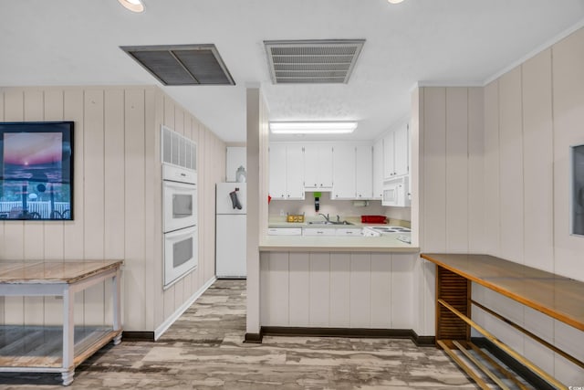 kitchen with light countertops, visible vents, white cabinetry, a sink, and white appliances