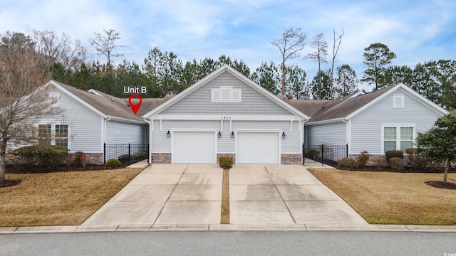 view of front of house featuring stone siding, concrete driveway, fence, and an attached garage