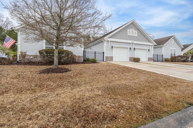 view of front of house with stone siding, concrete driveway, a front yard, and fence