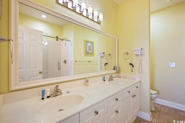 817 S Ocean Blvd Unit 105, North Myrtle Beach, SC 29582 - bathroom featuring toilet, a stall shower, tile patterned flooring, double vanity, and baseboards