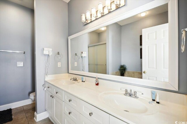 817 S Ocean Blvd Unit 105, North Myrtle Beach, SC 29582 - bathroom with tile patterned floors, toilet, a shower stall, baseboards, and double vanity