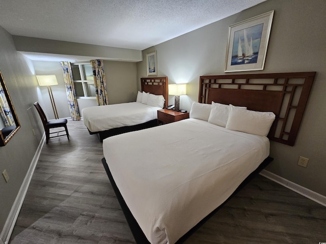 bedroom with a textured ceiling, dark wood finished floors, and baseboards