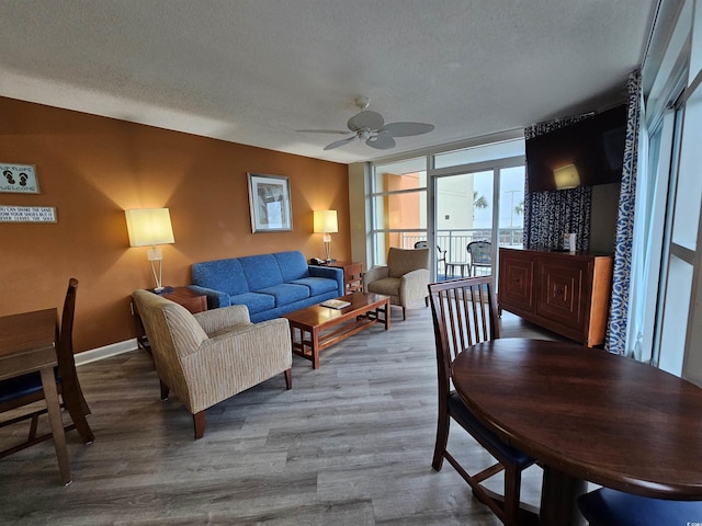 living area featuring a textured ceiling, baseboards, wood finished floors, and floor to ceiling windows