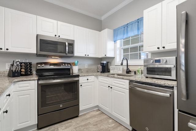 kitchen with light stone counters, stainless steel appliances, ornamental molding, white cabinets, and a sink