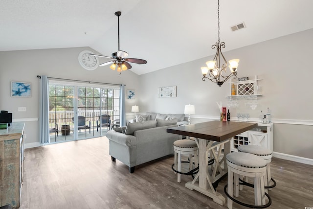 living room featuring lofted ceiling, ceiling fan with notable chandelier, visible vents, baseboards, and dark wood finished floors